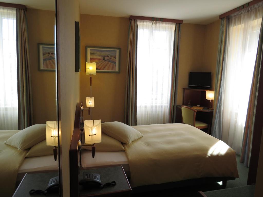 a hotel room with two beds and two windows at Hôtel du Port in Lausanne