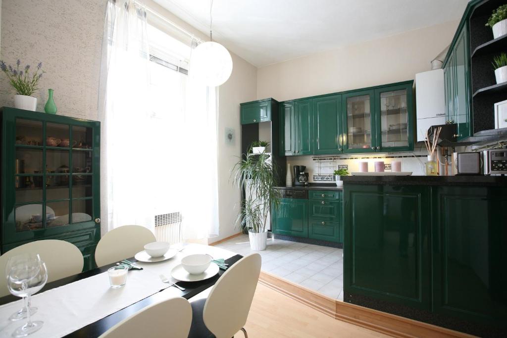 eine Küche mit grünen Schränken sowie einem Tisch und Stühlen in der Unterkunft Apartment Karolina in Prag