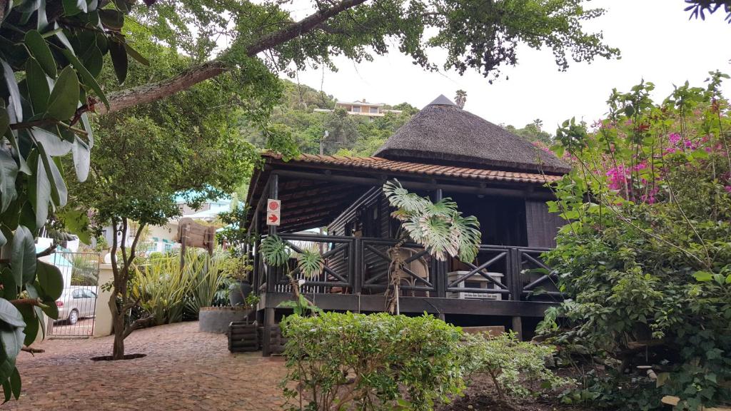 a small building with a thatched roof in a garden at Waterside Lodge in Wilderness