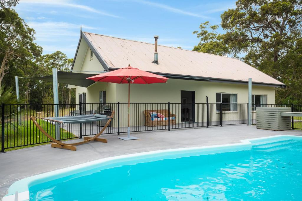
a white swimming pool with a blue umbrella at Bush Retreat With Private Pool in Narooma
