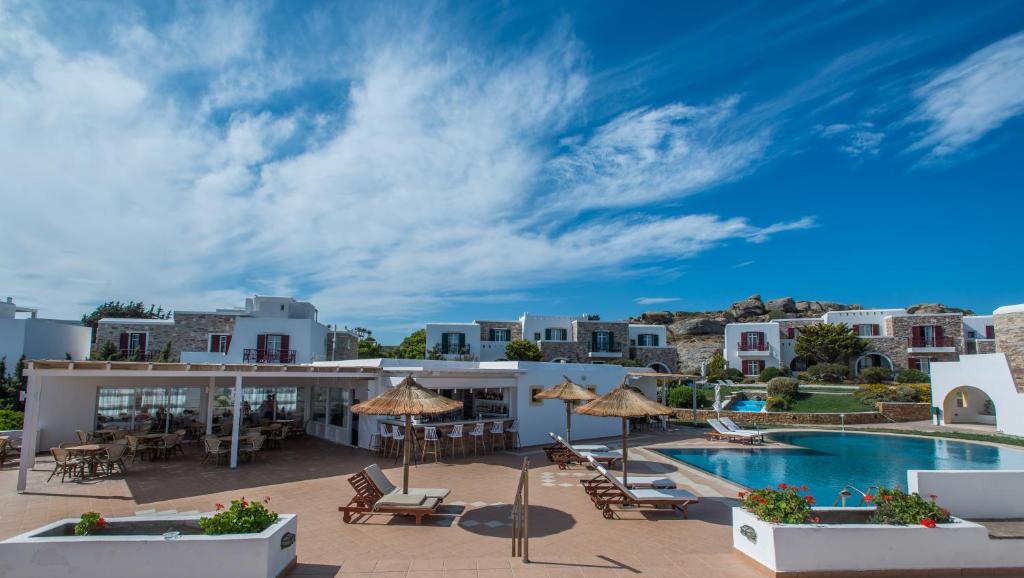 uma vista para um resort com uma piscina, mesas e cadeiras em Naxos Palace Hotel em Stelida