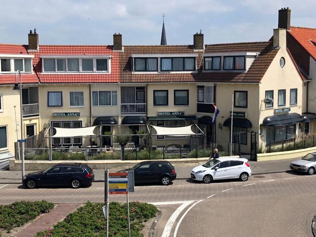 een groep auto's geparkeerd voor een gebouw bij Hotel Anna in Zandvoort