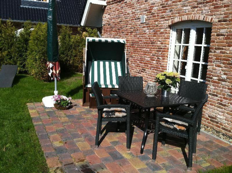 a black table and chairs on a brick patio at Haus-Sonnenschein in Tinnum