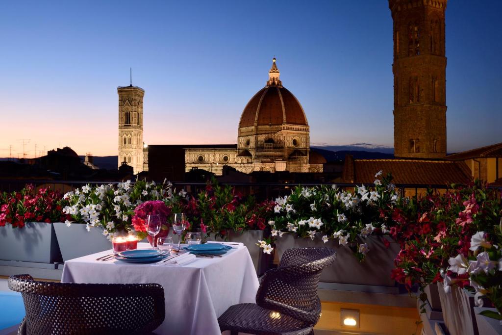 einen Tisch auf einem Balkon mit Blumen und einem Gebäude in der Unterkunft San Firenze Suites & Spa in Florenz