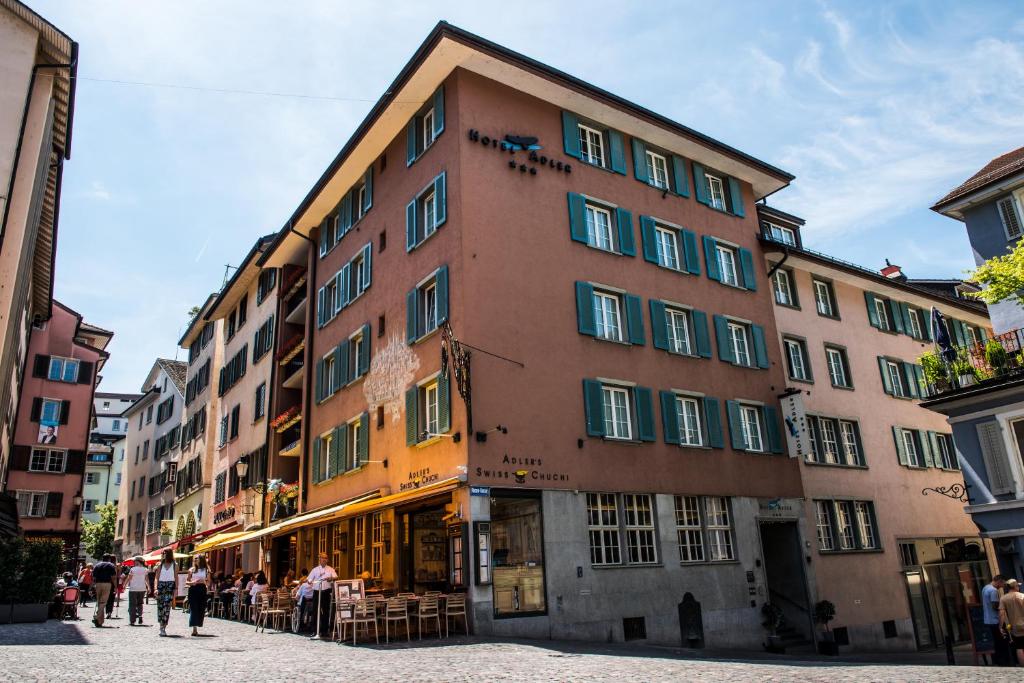 Un grand bâtiment avec des personnes debout à l'extérieur dans l'établissement Hotel Adler Zürich, à Zurich