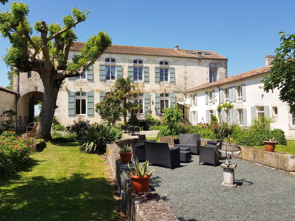 un patio con sillas, un árbol y un edificio en Domaine de Chantageasse, en Asnières-la-Giraud