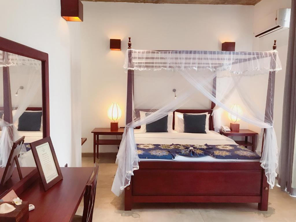 マウントラビニアにあるCoza Ceylonのベッドルーム(天蓋付きベッド1台、鏡付)