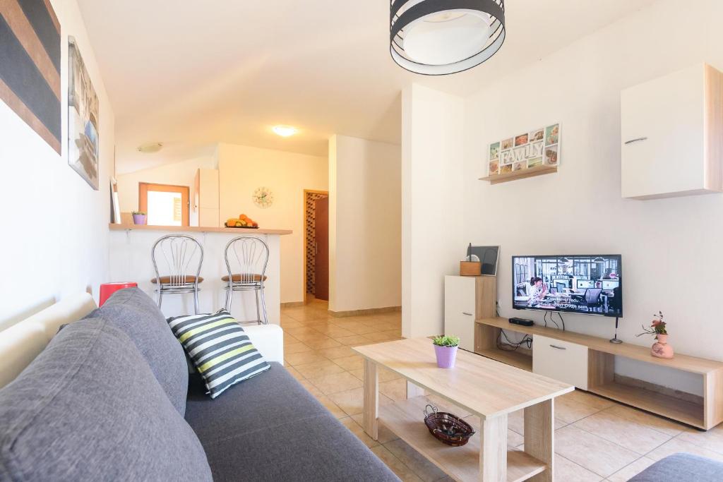 Una sala de estar con un sofá azul y un televisor. en Apartments Kostijal, en Zadar