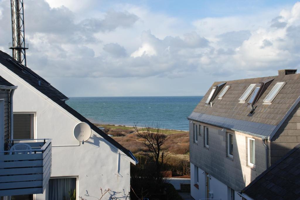 een uitzicht op de oceaan vanaf twee gebouwen bij Haus Nordlicht in Helgoland