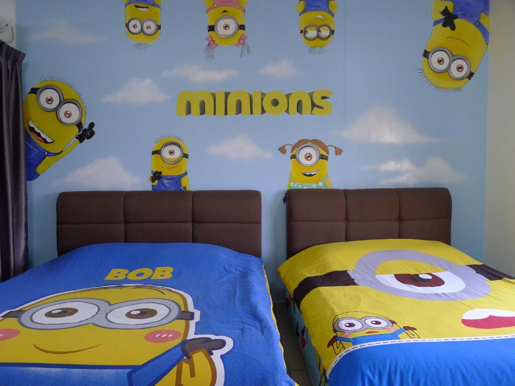 1 dormitorio con 2 camas con minions en la pared en KiddyPalace@Meridin en Nusajaya