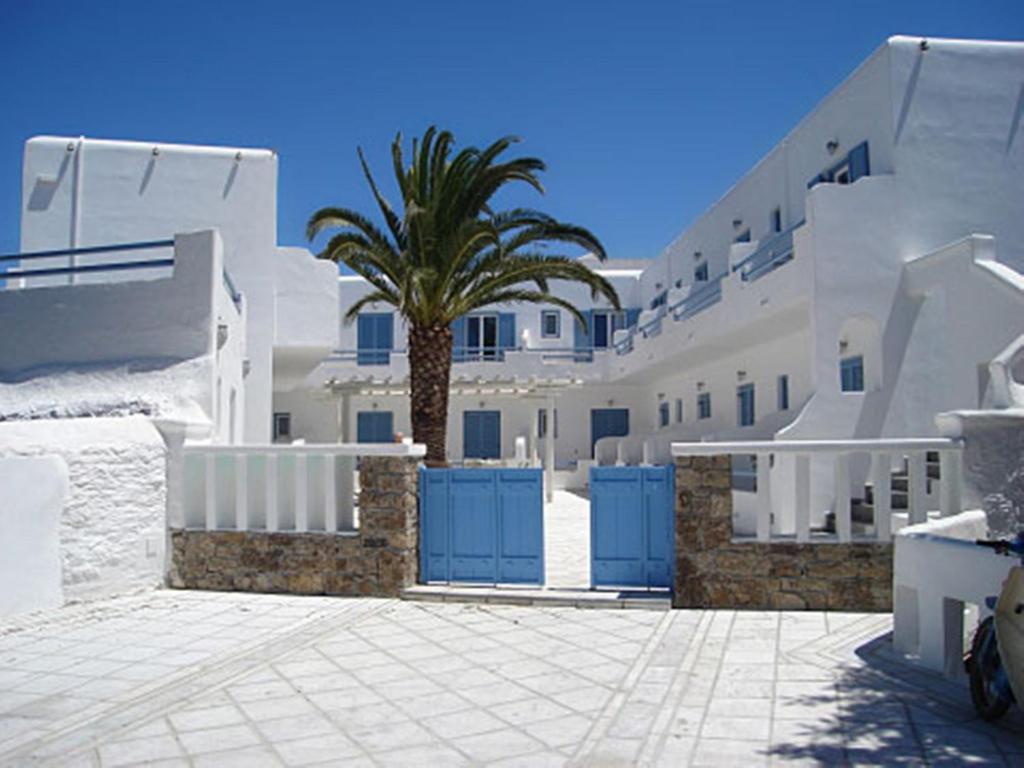 a palm tree in front of a row of white buildings at Magas Hotel in Mikonos