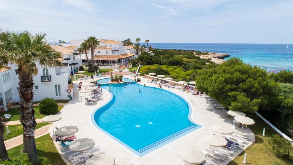 an aerial view of a resort pool with chairs and umbrellas at Grupotel Aldea Cala'n Bosch in Cala en Bosc