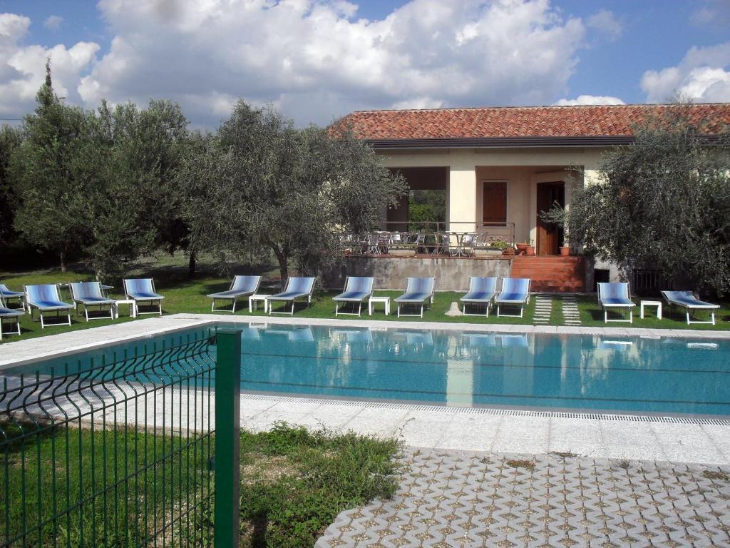 a swimming pool with chairs and a house at Agriturismo Ca' Licante in Bardolino