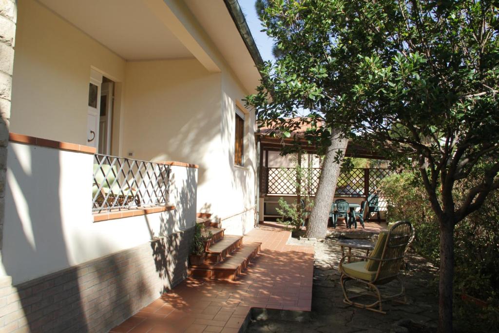 eine Veranda eines Hauses mit Stühlen und einem Baum in der Unterkunft VIA FIRENZE in Marina di Castagneto Carducci