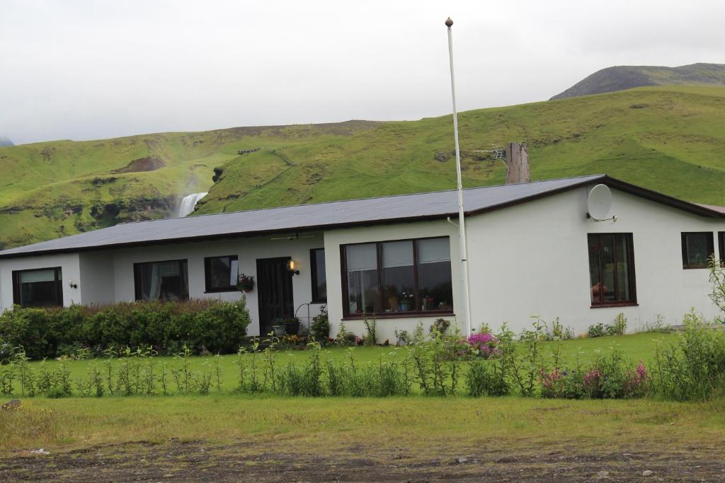 een wit huis met een heuvel op de achtergrond bij Fosstún Guesthouse in Skogar