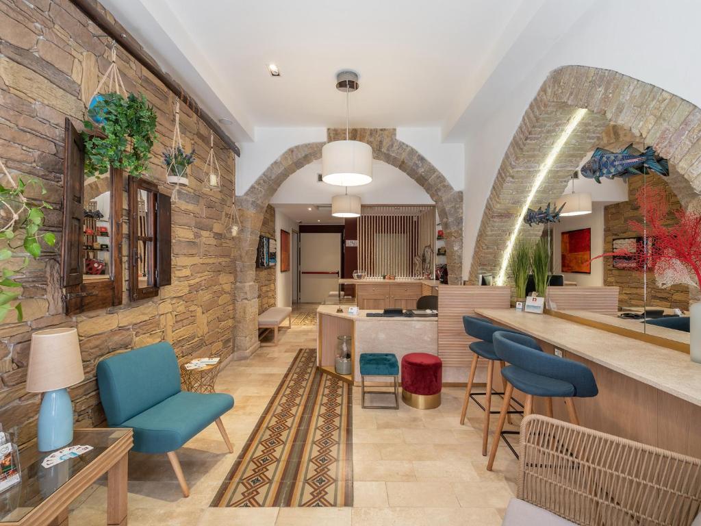 a lobby with a stone wall and blue chairs at Nichotel in Carloforte