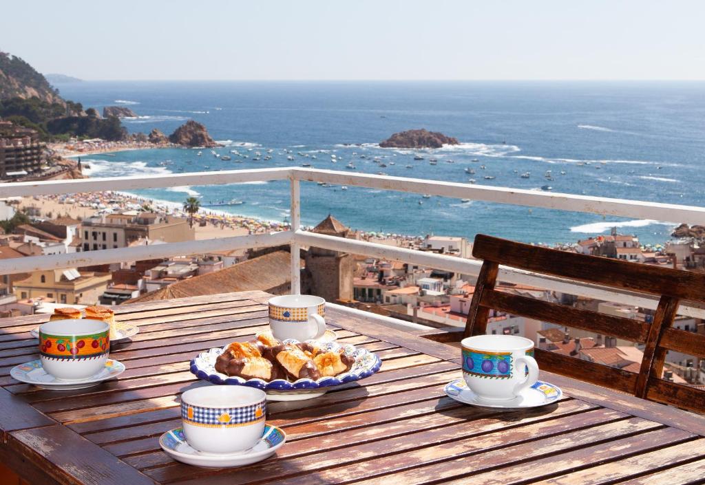 a table with cups of coffee and food on a balcony at Lets Holidays Apartment Costa Brava in Tossa de Mar