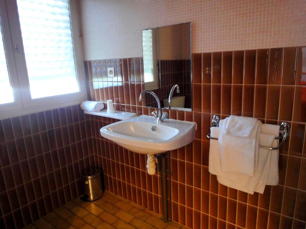 a bathroom with a sink and a mirror and towels at Hotel Restaurant La Grenouillère in Vitré