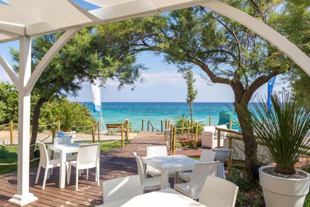 a patio with tables and chairs and the ocean at AquariumResidence in San Pietro in Bevagna