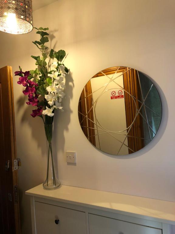 Luxurious Apartment "N22" في لندن: إناء من الزهور على منضدة مع مرآة