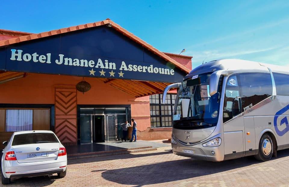 un autobus parcheggiato di fronte a un'agenzia di sicurezza dell'hotelarma akhtar di Hôtel Jnane Ain Asserdoune a Oulad Yaïch
