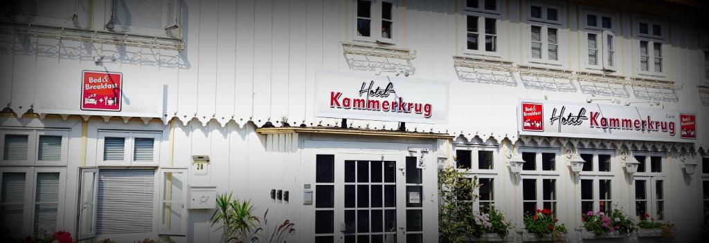 ein weißes Gebäude mit Schildern an der Seite in der Unterkunft Hotel Kammerkrug in Bad Harzburg