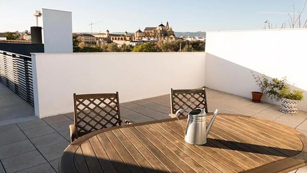 Apartamentos Turísticos Córdoba Califal في قرطبة: طاولة خشبية وكرسيين على شرفة
