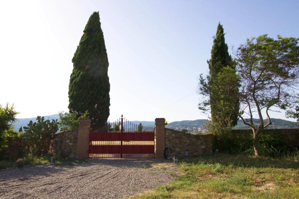 een hek met een rode poort en twee bomen bij B&B Bagnarello73 in Suvereto