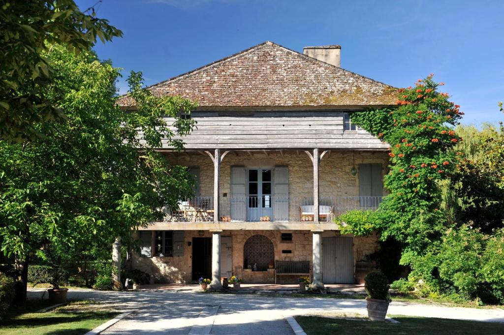 an old house with a porch and a tree at Moulin de Labique in Saint-Eutrope-de-Born