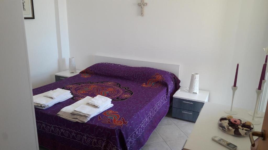 a room with a purple bed with towels on it at SicilyHome in Marzamemi