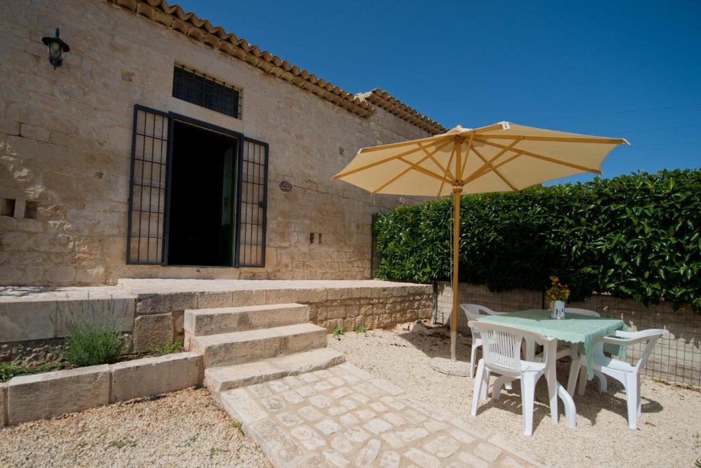 une table avec un parasol jaune, une table et des chaises dans l'établissement Antica Masseria Adamo, à Sampieri