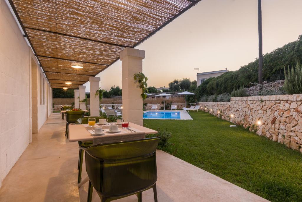 un patio con mesa, sillas y piscina en Casale Ramunno en Ostuni