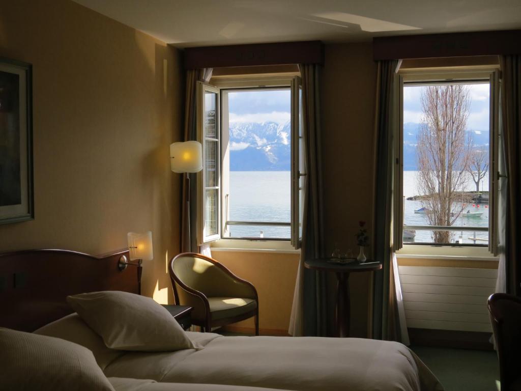 a hotel room with a bed and two windows at Hôtel du Port in Lausanne