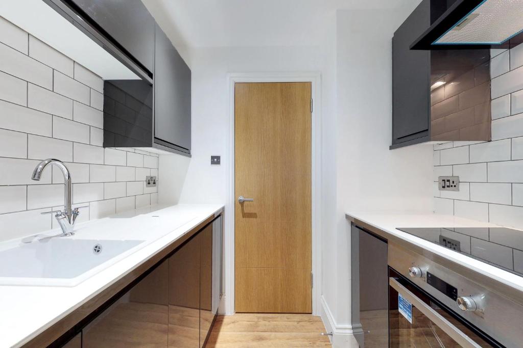 a kitchen with a sink and a wooden door at Superb 2 beds 2 baths New Apartment w/ Garden+Patio in Bournemouth