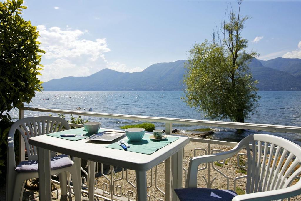 uma mesa e cadeiras numa varanda com vista para a água em Casa Azzurra em Germignaga