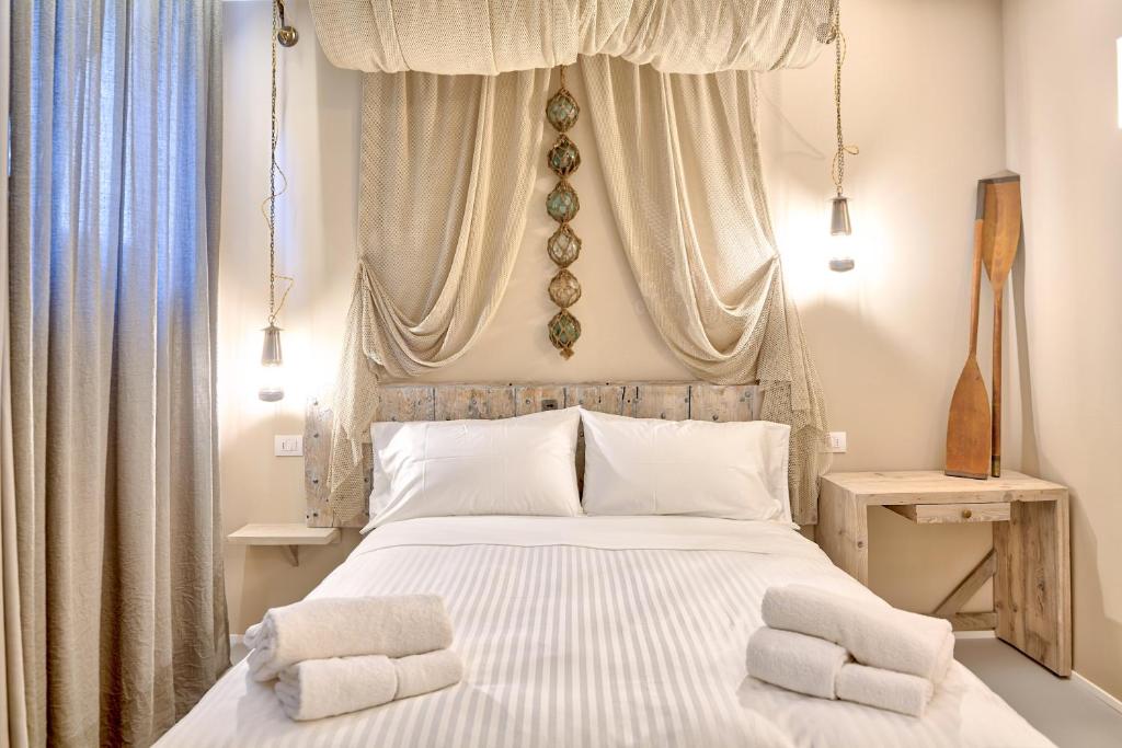 1 dormitorio con 1 cama blanca y 2 toallas en A'Mare Luxury Rooms en Diano Marina