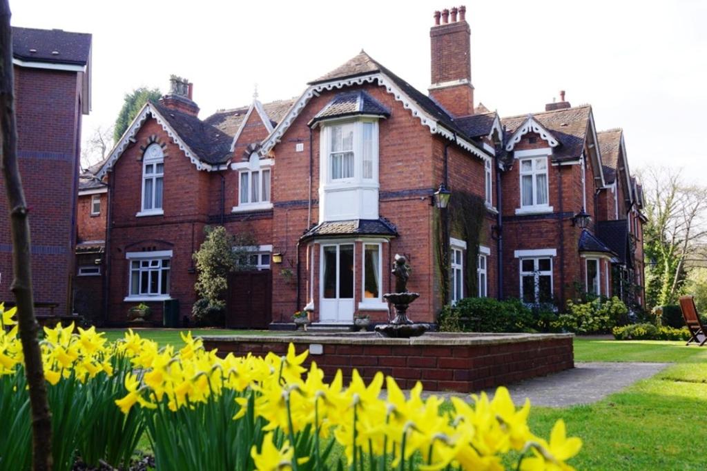 a house with yellow flowers in front of it at Hillscourt in Barnt Green