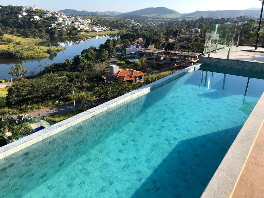 a swimming pool with a view of a river and a city at Suítes de Luxo Paraíso de Minas Escarpas in Capitólio