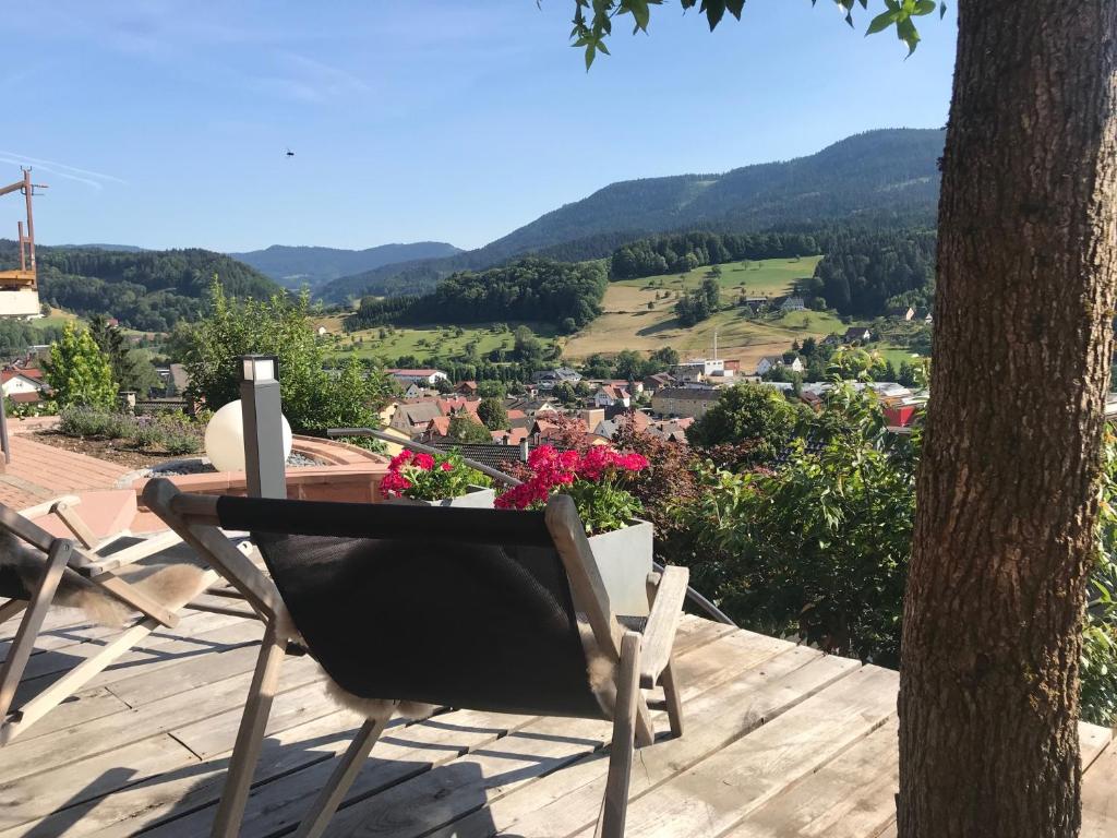 une chaise assise au-dessus d'une terrasse avec un arbre dans l'établissement Schwarzwald Lodge Oppenau, à Oppenau