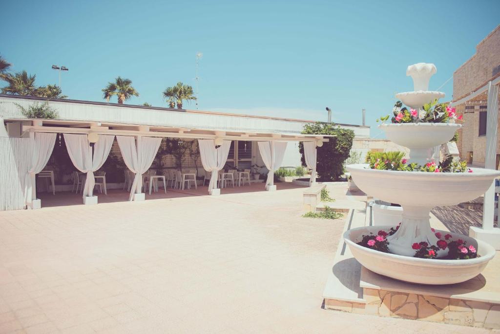 a patio with two large white vases with flowers at Hotel San Giovanni in Polignano a Mare