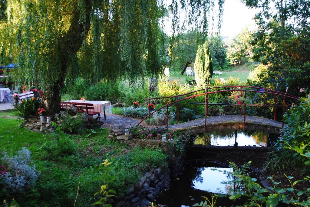 un puente sobre un estanque en un jardín en Le Moulin du Bignon en Lassy