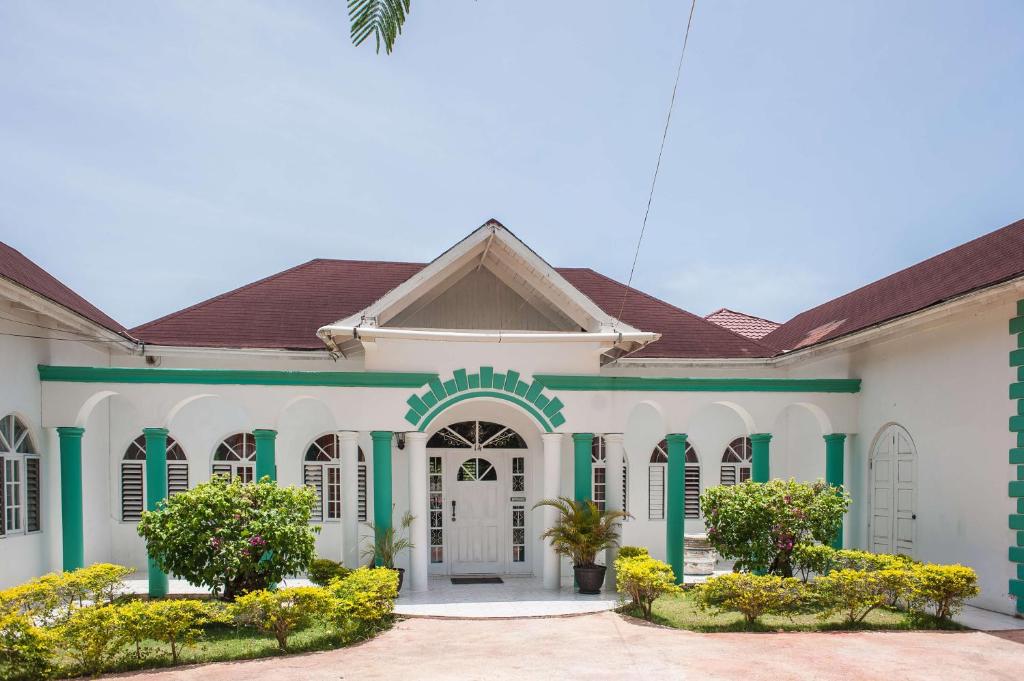 un grande edificio bianco con finiture verdi e bianche di Diamond Villa Guest House a Montego Bay