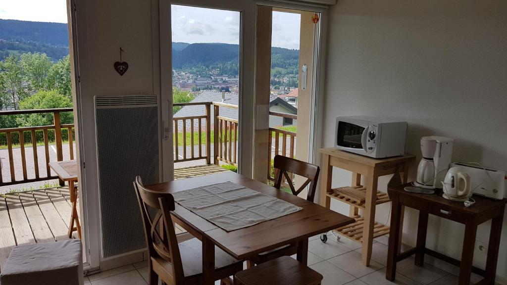 eine Küche mit einem Tisch und einer Mikrowelle auf dem Balkon in der Unterkunft F2 SUR LES HAUTEURS DE GERARDMER in Gérardmer