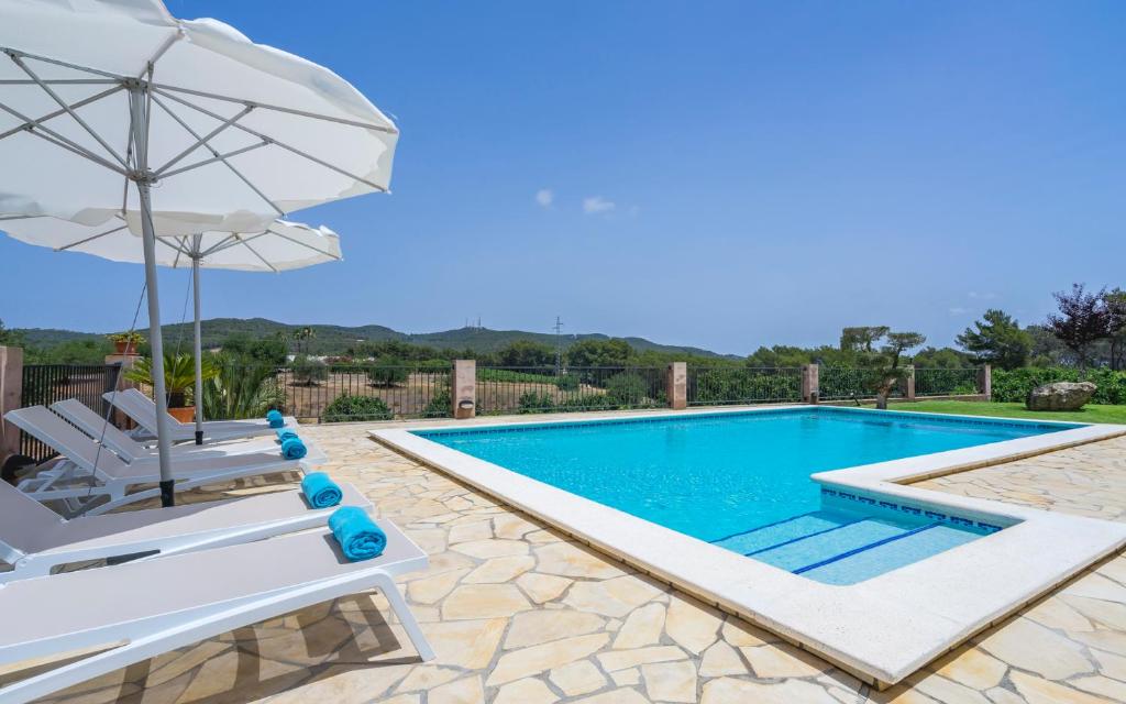 a swimming pool with two chairs and an umbrella at Can Roig in Santa Gertrudis de Fruitera