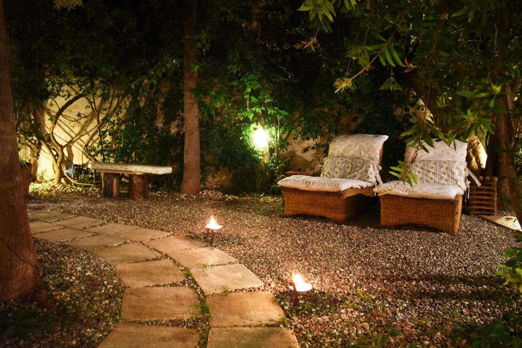 dos sillas y un banco en un jardín por la noche en B&B Al Vecchio Glicine, en Torre Canne