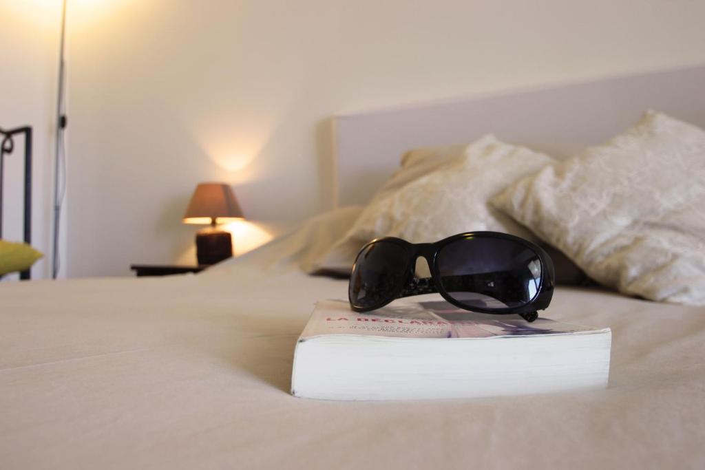 a pair of sunglasses sitting on a book on a bed at Villa Ghiatone in Pietrosella