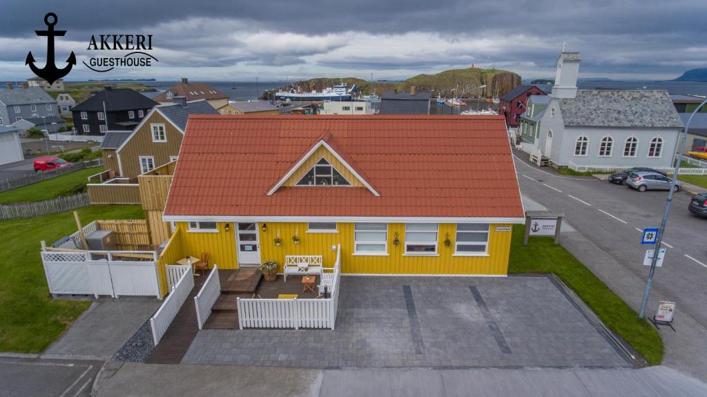 a yellow house with an orange roof on a street at Akkeri Guesthouse in Stykkishólmur