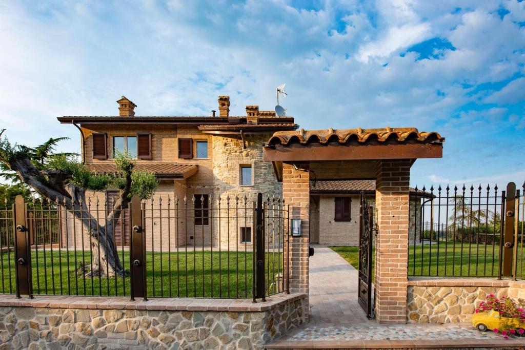 una puerta frente a una casa con una valla en B&B Madonna Carradori Country en Offagna