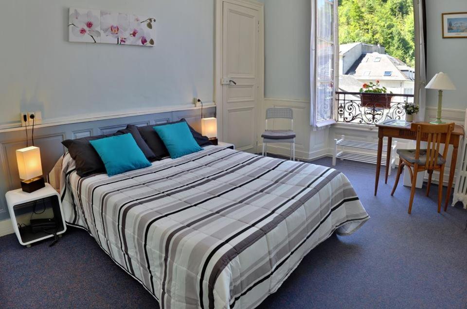 a bedroom with a bed and a desk and a window at Hotel Richelieu in Eaux-Bonnes