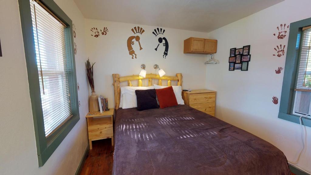a bedroom with a bed in a room with windows at Hot Tub, Kokopelli Kabyn, Cute and Cozy! in Blanding